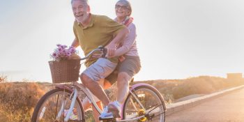 joy and happiness for adult married couple start and have fun traveling on the same bike in outdoor activity with sun backlight on the background. clear and bright image for smile and laugh people.